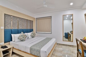 A modern hotel room with a large bed, a desk, and a chair.