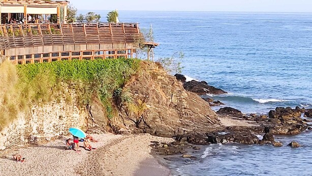 A coastal hotel with a beach view, rocky shoreline, and a structure with a sloped roof overlooking the sea. - Benalmar Playa (Benalmádena)