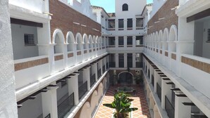A courtyard with a central fountain, surrounded by white walls and arches, and a tiled floor. - Benalmar Playa (Benalmádena)