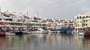 A marina with boats docked, waterfront buildings with shops, and a bridge connecting the areas. - Benalmar Playa (Benalmádena)