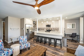 Una cocina moderna con una isla central, taburetes de bar y una mesa de comedor.
