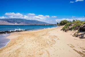 A beach with a clear view of the ocean and distant mountains.