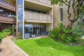 A modern building with a glass entrance, outdoor seating, and a well-maintained garden.