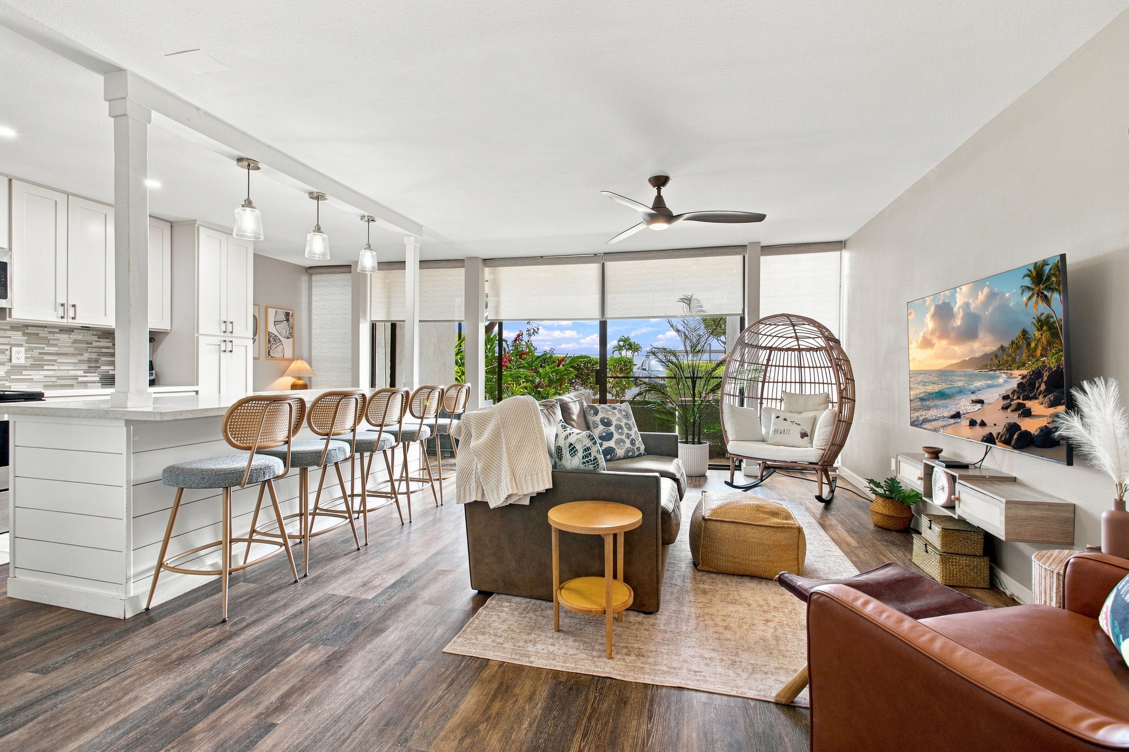 Un espace de vie moderne à aire ouverte comprenant une cuisine, un coin repas et un espace détente avec vue sur l’extérieur.