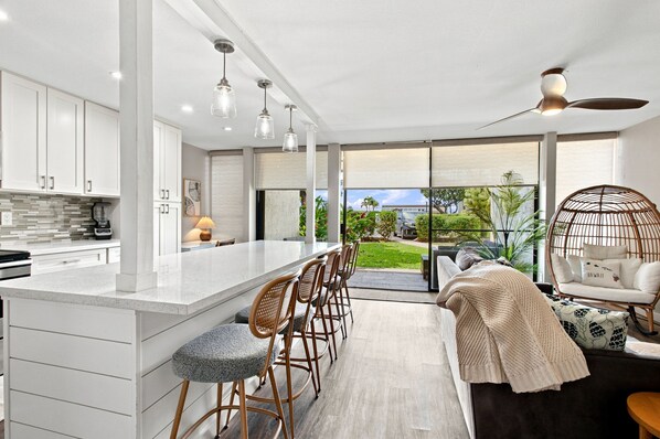 A modern kitchen with a large island, bar stools, and a view of the outdoors.