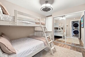 Une chambre avec des lits superposés, une échelle, un lave-linge et un miroir.