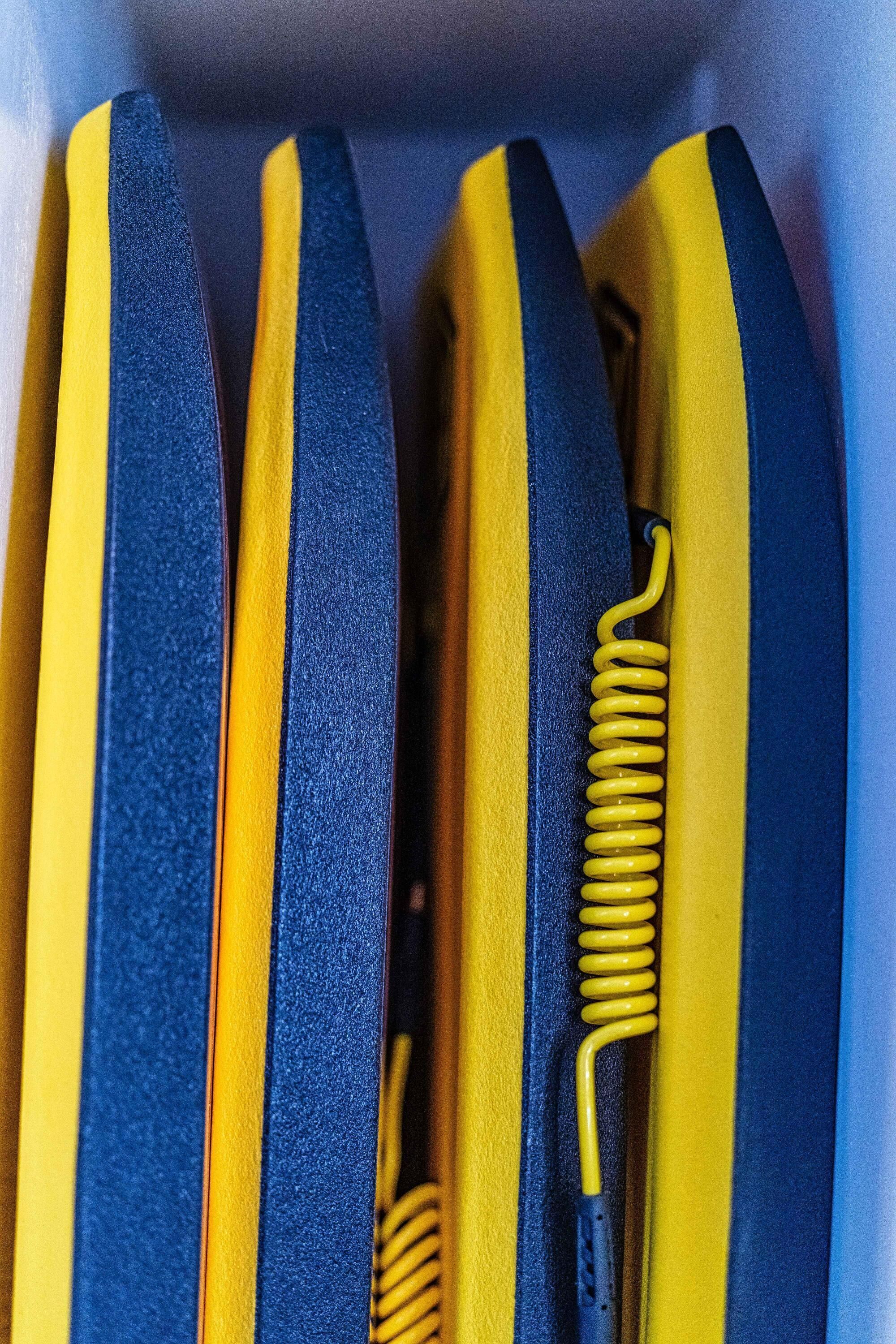 A close-up of a set of yellow and blue striped objects, possibly tools or equipment, with a coiled yellow spring visible.