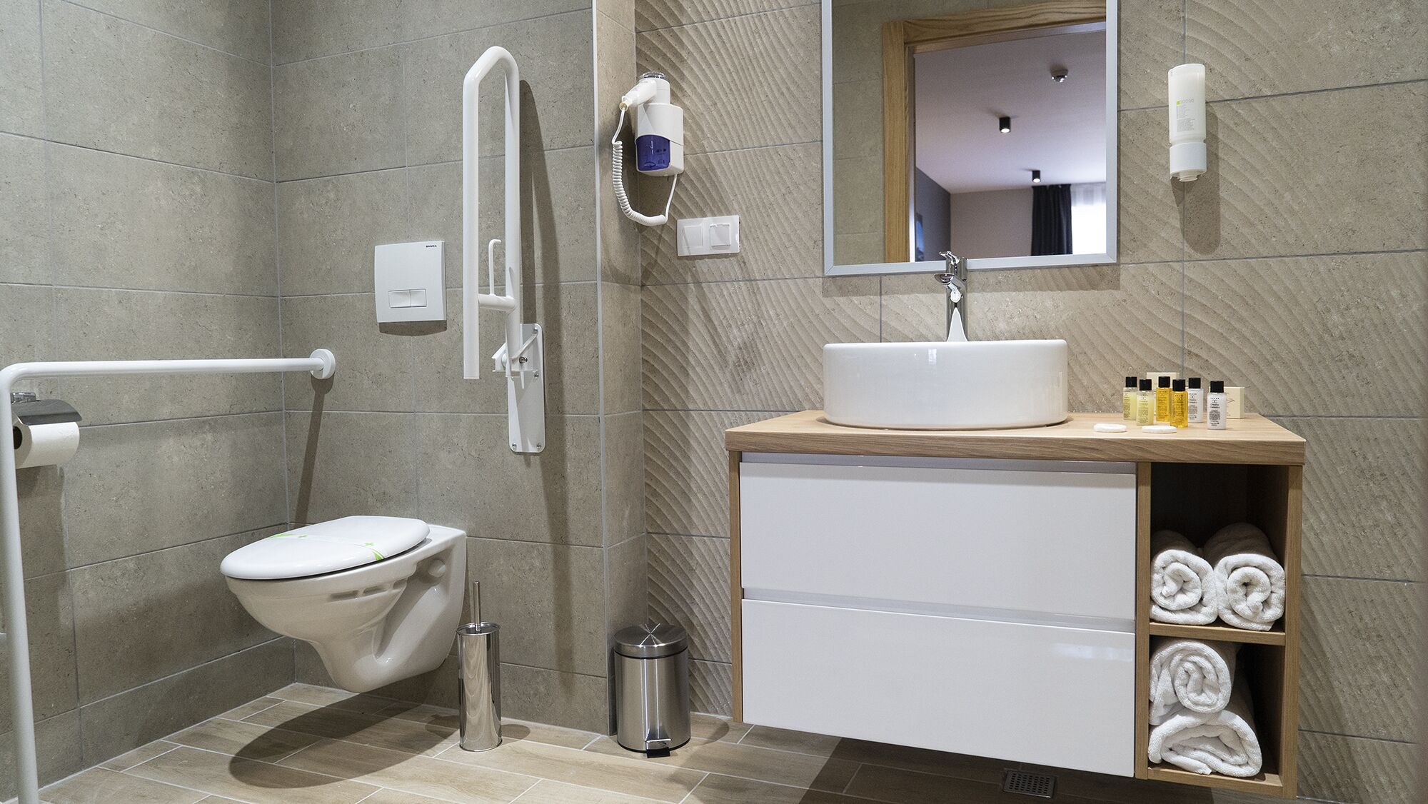 A modern bathroom with a toilet, sink, and hand dryer.