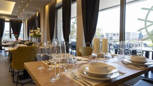 Un restaurant où les tables sont dressées pour le dîner, avec des bougies et des verres à vin.
