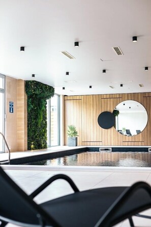 A modern indoor pool area with a wooden wall, a vertical garden, and a round mirror. - Ha Hotel Mostar (Mostar)