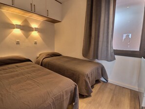 Un dormitorio con dos camas individuales, techo de madera y ventana con cortinas.