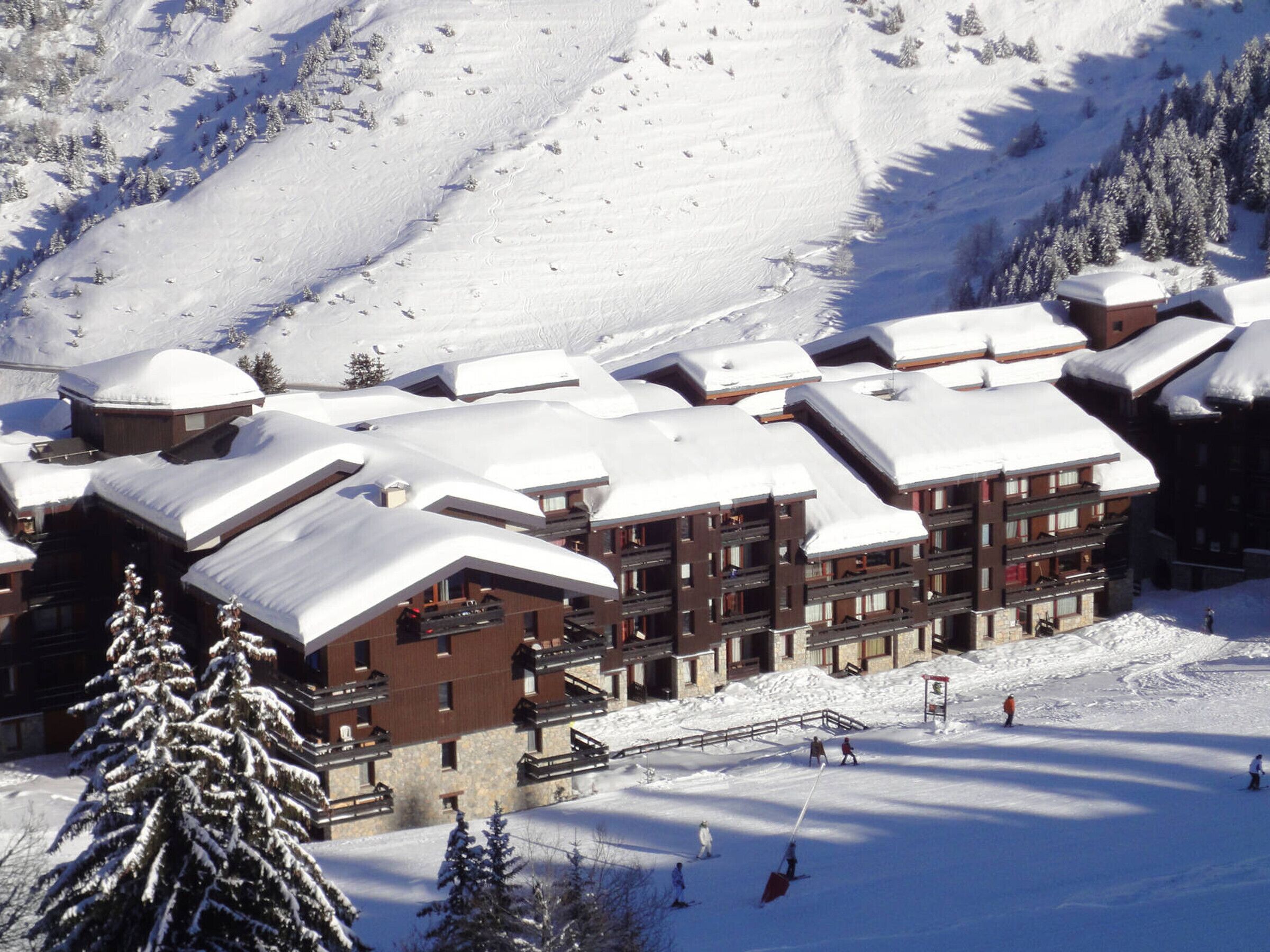A snow-covered lodge with multiple floors, ski slopes, and a ski lift.