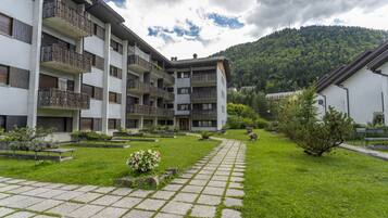 Un edificio a più piani con balconi, un cortile lastricato e montagne sullo sfondo.