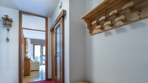 A hallway with a wooden bench, a coat rack, and a door leading to another room.