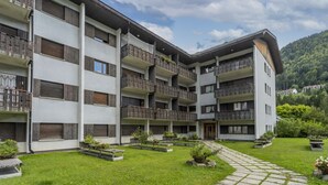 A multi-story hotel with balconies, a paved courtyard, and a mountainous backdrop. - GuestHost - Typical vintage flat with terrace (overlooking the Julian Alps!) That can accommodate up to 4 people, located in a quiet area with common garden a stone's throw from the center of Tarvisio. Thanks to its strategic position, from the apartment (Tarvisio)