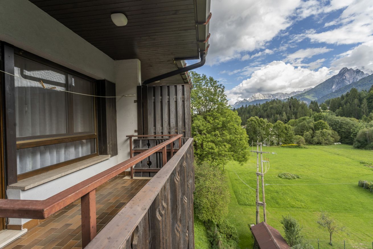 Ein Balkon mit Holzgeländer mit Blick auf eine grüne Landschaft und Berge.