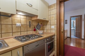 Une cuisine équipée d’une cuisinière à gaz, d’un four, d’un lave-vaisselle et d’un plan de travail recouvert de carreaux.