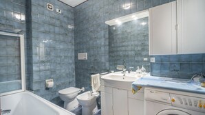 A bathroom with a bathtub, toilet, bidet, sink, and washing machine. - GuestHost - Typical vintage flat with terrace (overlooking the Julian Alps!) That can accommodate up to 4 people, located in a quiet area with common garden a stone's throw from the center of Tarvisio. Thanks to its strategic position, from the apartment (Tarvisio)
