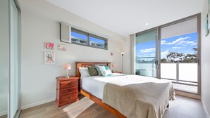 A bedroom with a large bed, a nightstand, a dresser, and a window with a view. - Wentworthville 2 Bedrooms 2 Bathrooms with Free Parking by KozyGuru (Wentworthville)