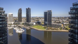 A high-rise building with a marina in the foreground, surrounded by other modern buildings. - Docklands high level 1 Bedroom Apartment with pool by KozyGuru (Docklands)