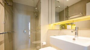 A modern bathroom with a glass-enclosed shower, a white sink, and a toilet. - Docklands high level 1 Bedroom Apartment with pool by KozyGuru (Docklands)