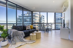 Un saló modern amb una finestra gran, un sofà, una taula de centre i una zona de menjador.