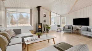 Una sala de estar acogedora con chimenea, asientos cómodos y ventanas amplias.
