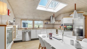 Una cocina moderna con tragaluz, electrodomésticos de acero inoxidable y una zona de comedor blanca.