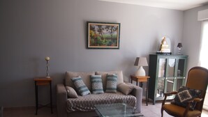 Ein Wohnzimmer mit einer Couch, einem Glastisch, einem Sessel, einer Lampe und einem Schrank.