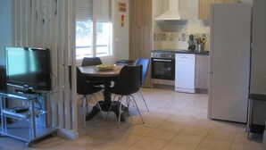 Eine kompakte Küche mit Essbereich, Fernseher und Kühlschrank.
