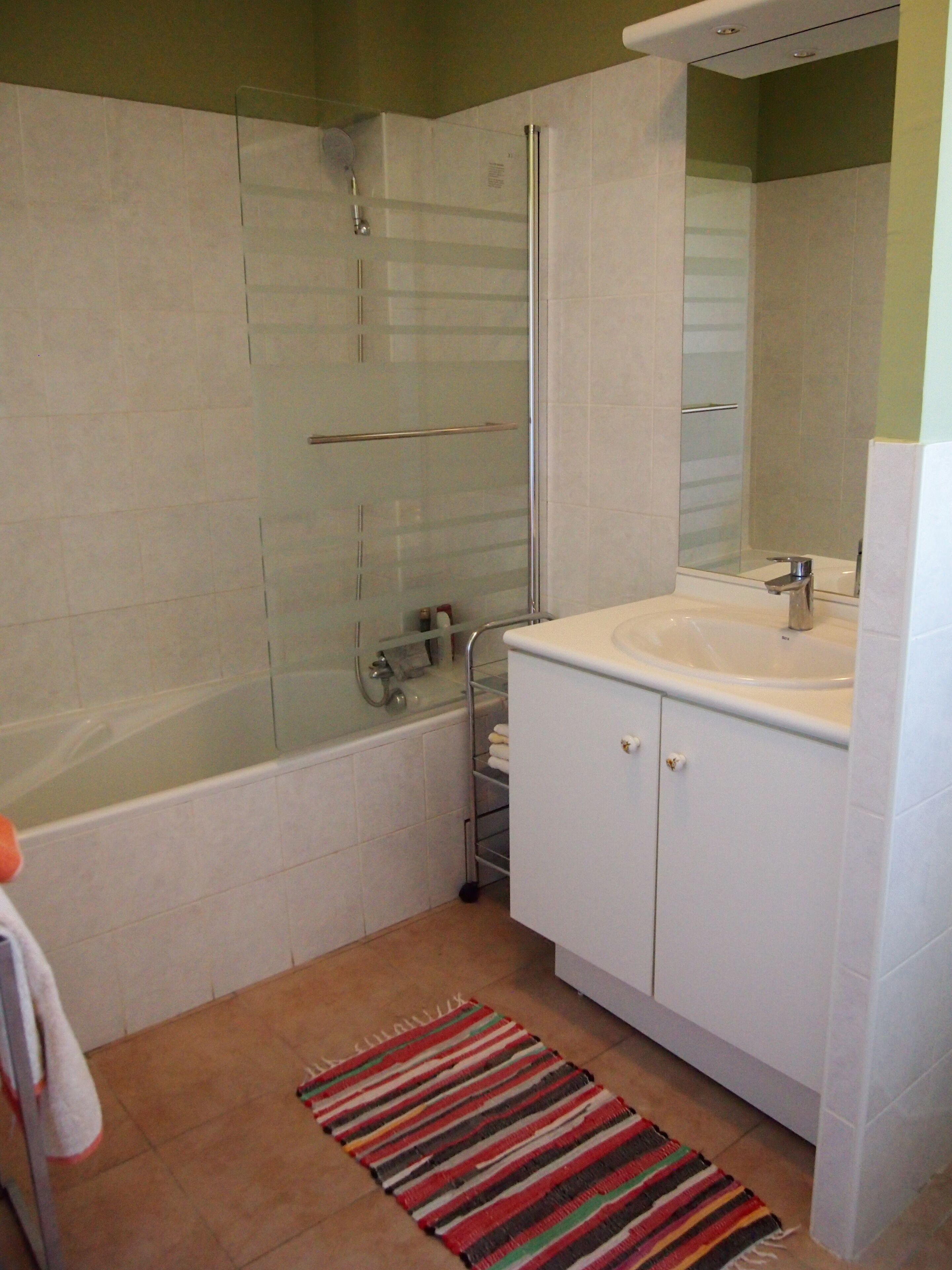 Une salle de bain avec une douche à parois de verre, un lavabo blanc et un meuble de rangement.