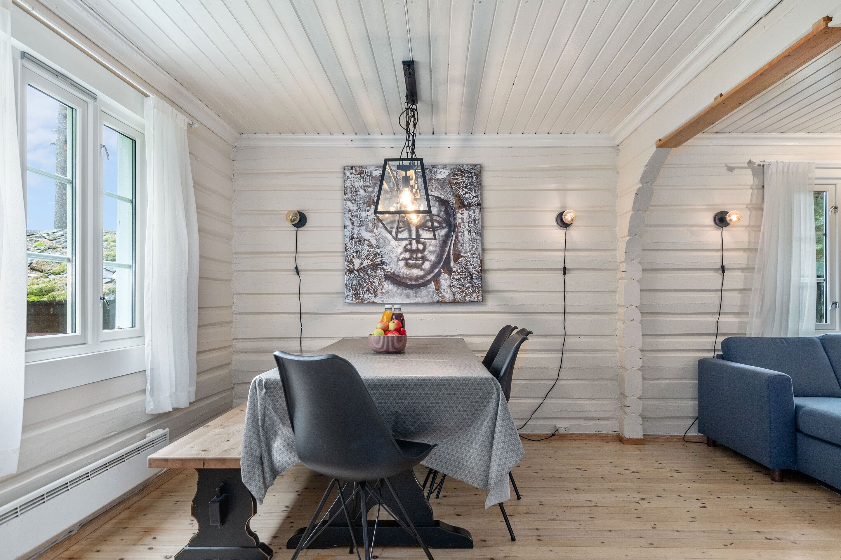 Uma sala de jantar com uma mesa de madeira, cadeiras pretas e um quadro na parede.
