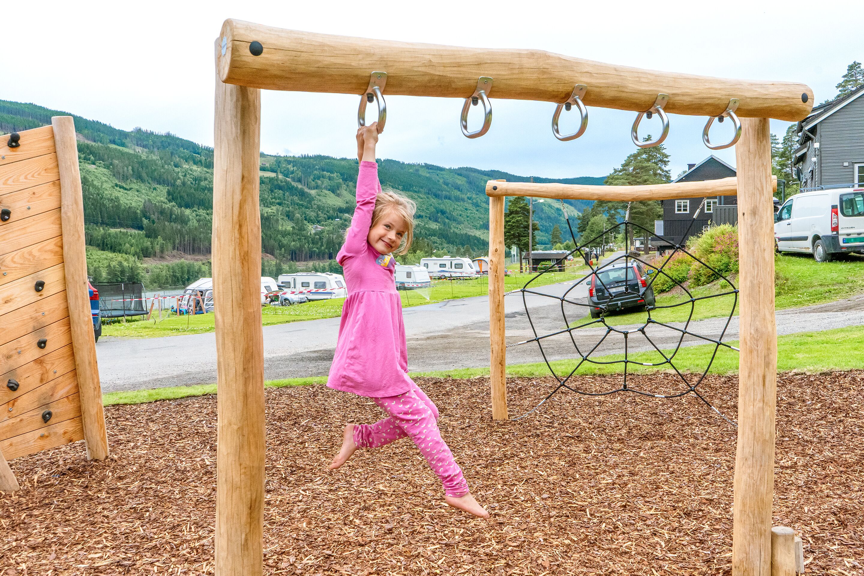 Un niño jugando en un parque infantil de madera con aros metálicos y una red.