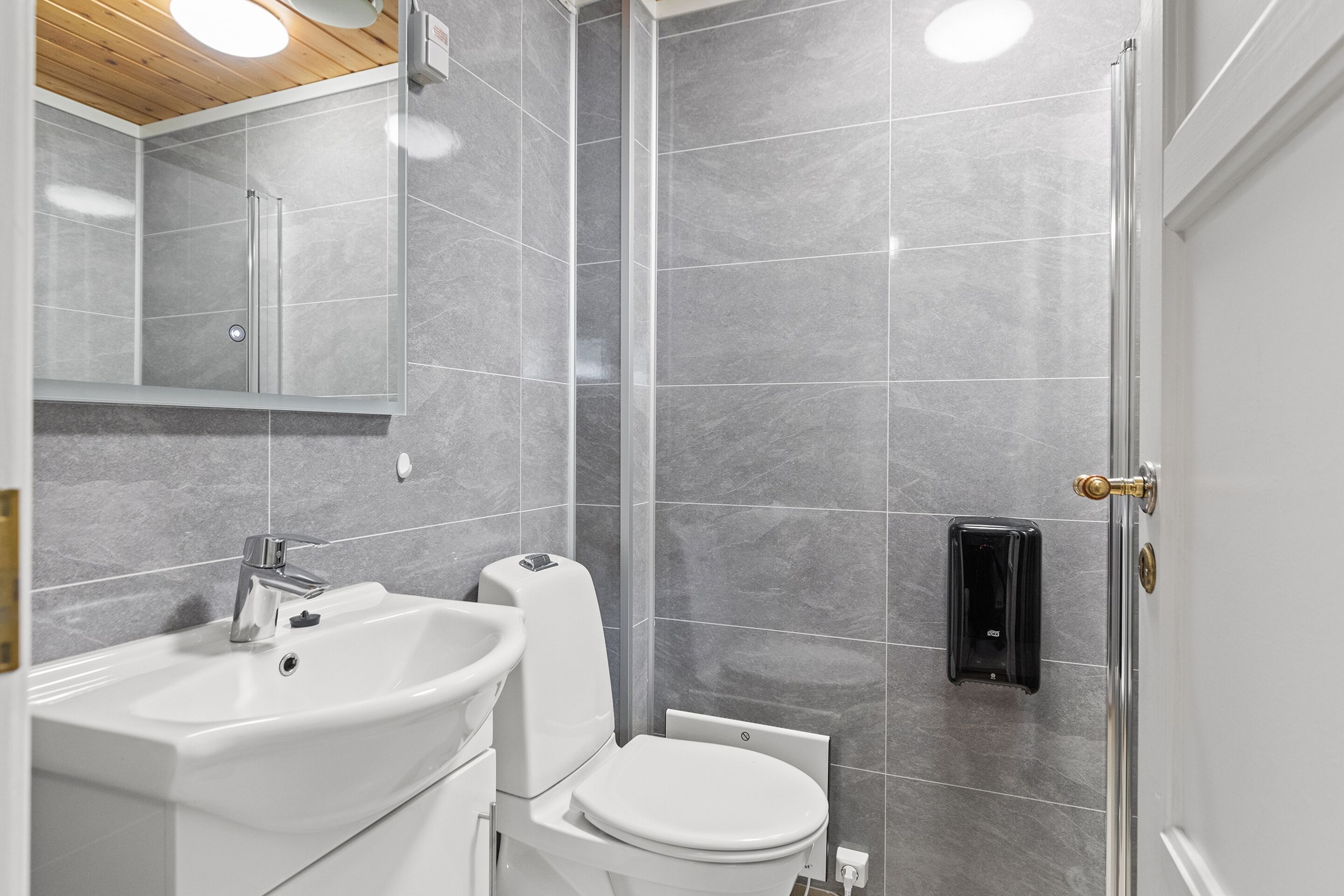 Une salle de bain moderne avec un lavabo blanc, des toilettes et un espace douche.