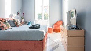 Une chambre à coucher avec un lit, un bureau, une chaise, une plante en pot et une fenêtre.