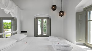 Ein Hotelzimmer mit einem großen Bett, zwei Nachttischlampen, einem Kleiderschrank und Blick auf Grün.