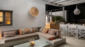 Ein moderner Außenbereich mit einer gepolsterten Couch, einem Glastisch und einem Esstisch mit Stühlen.