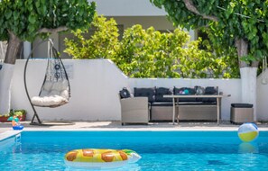 A pool area with a hanging chair, a sofa, and a table.