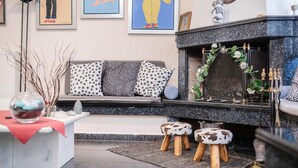 Ein modernes Wohnzimmer mit Kamin, einer Couch mit gemusterten Kissen und einem kleinen Tisch mit roter Tischdecke.