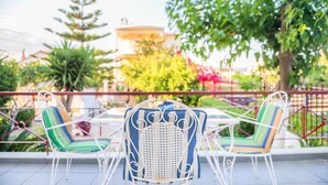 Ein Patio mit zwei weißen Metallstühlen und einem Tisch, umgeben von einem Metallzaun.
