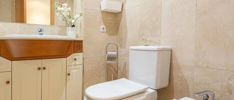 A bathroom with a toilet, sink, and mirror.