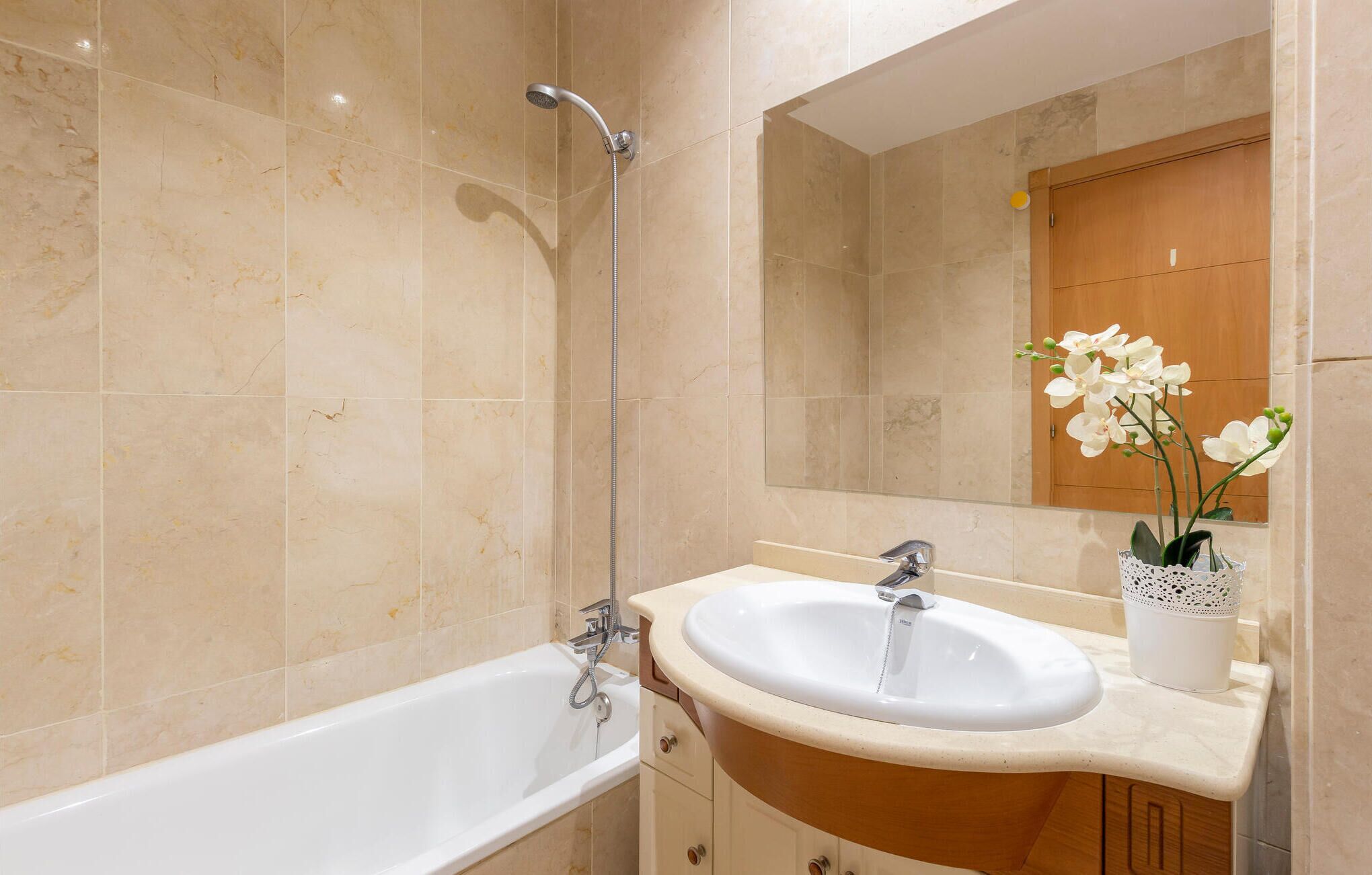 Un baño moderno con bañera, lavamanos y espejo.