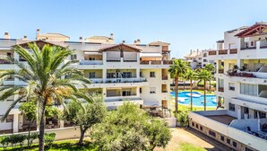 A multi-story hotel with balconies, a swimming pool, and palm trees. - Stunning apartment in Benalmádena with WiFi (Benalmádena)