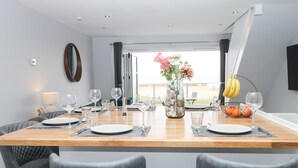 A dining area with a wooden table set for four, surrounded by grey upholstered chairs. - Ocean View (Hayling Island)