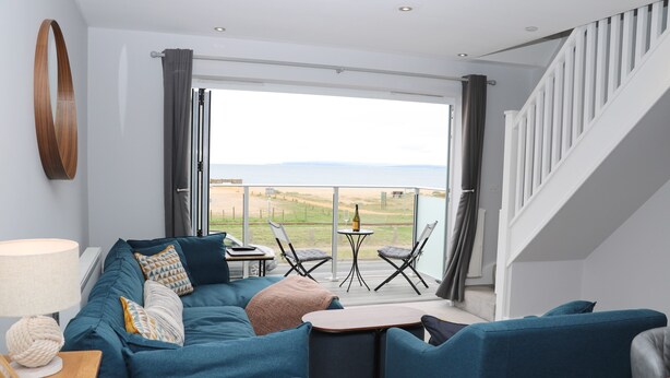 A modern living room with a sofa set, a coffee table, and a view of the outdoors. - Ocean View (Hayling Island)