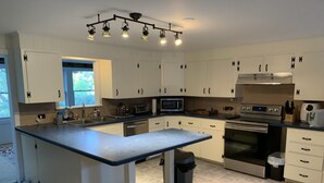 A modern kitchen with white cabinets, a large island, a microwave, an oven, and a sink. - Mountain View Farmhouse, pool/hot tub, fire pit, 4 seasons porch, game room (Millerton)
