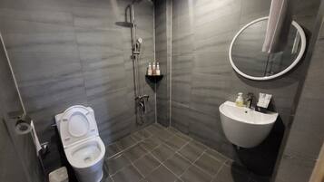 Un baño moderno con inodoro, lavabo, ducha y espejo.