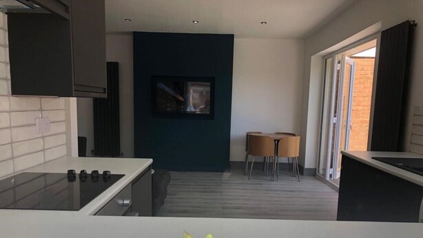 A modern kitchen with a black countertop, a dining area with two chairs, and a large window. - Lovely 3-bed House in Lytham Saint Annes (Lytham St. Anne's)