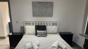 A neatly made bed with patterned bedding, two bedside tables, a decorative pillow, and a wall-mounted artwork. - Lovely 3-bed House in Lytham Saint Annes (Lytham St. Anne's)
