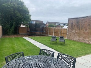 A backyard with a lawn, a trampoline, and a table with chairs. - Lovely 3-bed House in Lytham Saint Annes (Lytham St. Anne's)